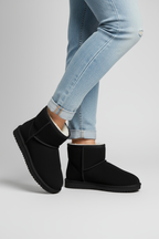 Women's black ankle boots with faux fur lining and flat sole worn with jeans