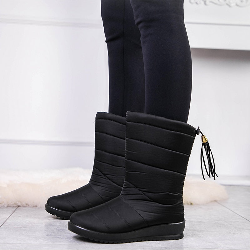 Black mid-calf quilted boots with side tassel, seam lines, and low-profile rubber sole