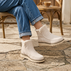 Beige women's suede-look ankle boots with faux fur lining, contrast stitching, worn with jeans