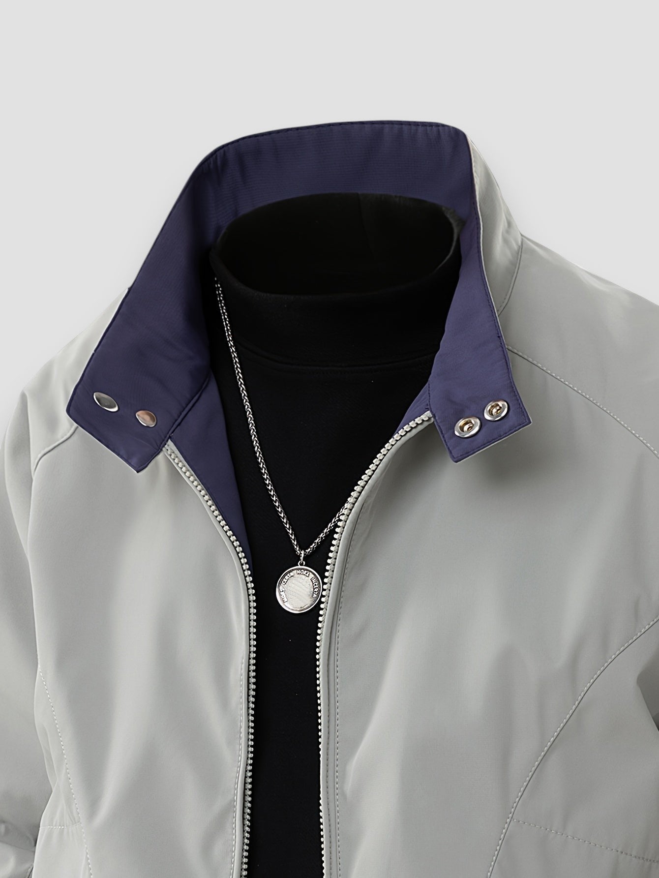 Light gray jacket close-up with full-zip front, snap collar, and buttoned shoulder tabs.
