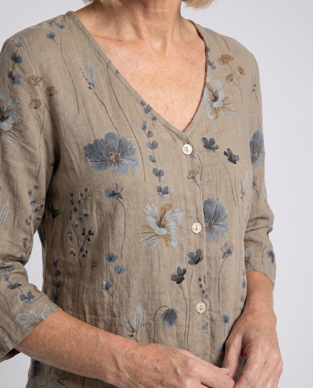 Women’s taupe floral V-neck blouse close-up with wooden button placket