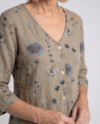 Women’s taupe floral V-neck blouse close-up with wooden button placket