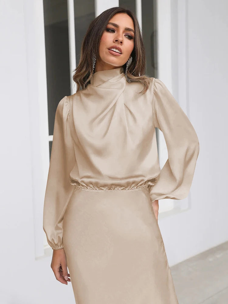 Beige satin midi dress with long sleeves, high neck, and ruched waist detail.