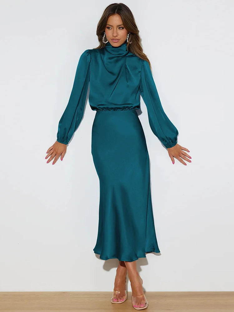 Teal satin midi dress with long sleeves and high neckline, arms slightly out.