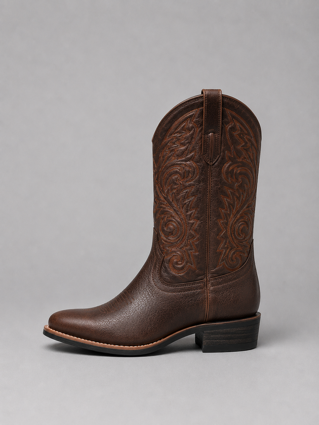 Brown leather cowboy boot with embossed western embroidery, pull tabs, stacked heel