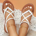 White open-toe flat sandals, crisscross straps, braided toe loops, gold ankle chain