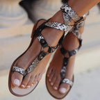 Women’s flat open-toe sandal with snake-print wrap straps and adjustable buckles