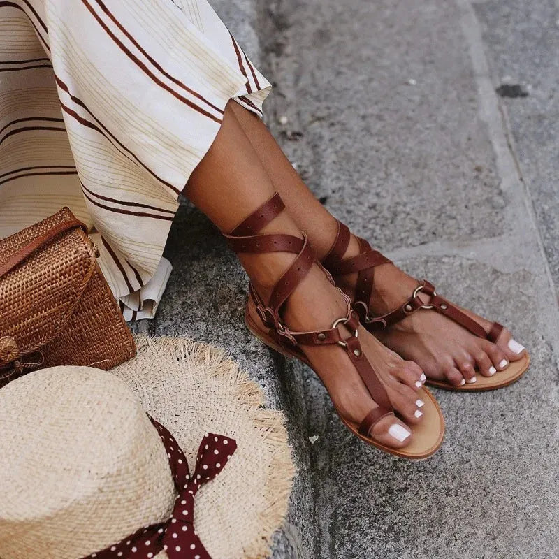 Women’s flat open-toe sandal with brown wrap straps and buckle ankle