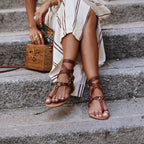 Women’s flat open-toe sandal with brown thong straps and ankle buckle