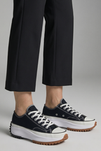 Women’s black trainers with white midsoles and leather platform sole, side view