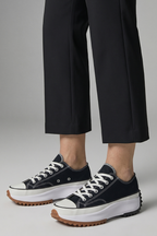 Women’s black trainers with brown tread leather platform sole, angled close-up