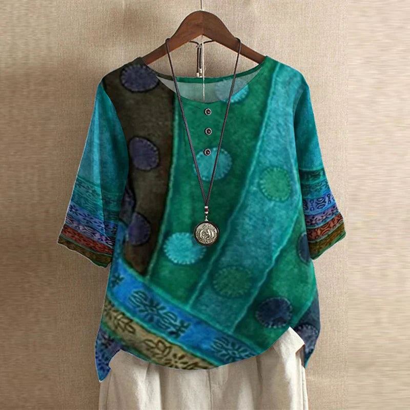 Women’s teal blouse with multicolor circular accents, short sleeves, round neck