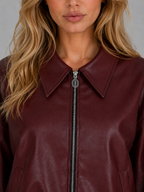 Burgundy leather zip-front jacket close-up with pointed collar and metal zipper