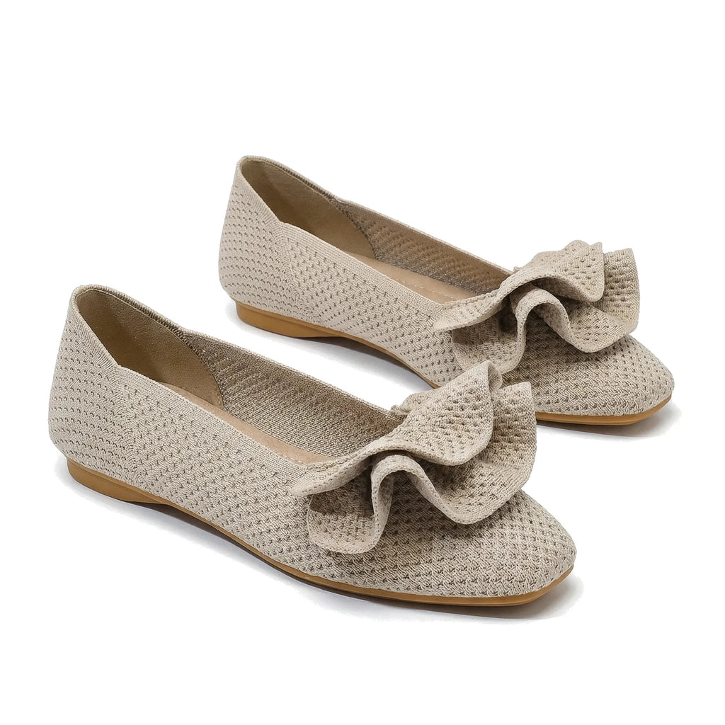 Light beige wide-fit slip-on knit shoes with arch support, bow detail, flat sole