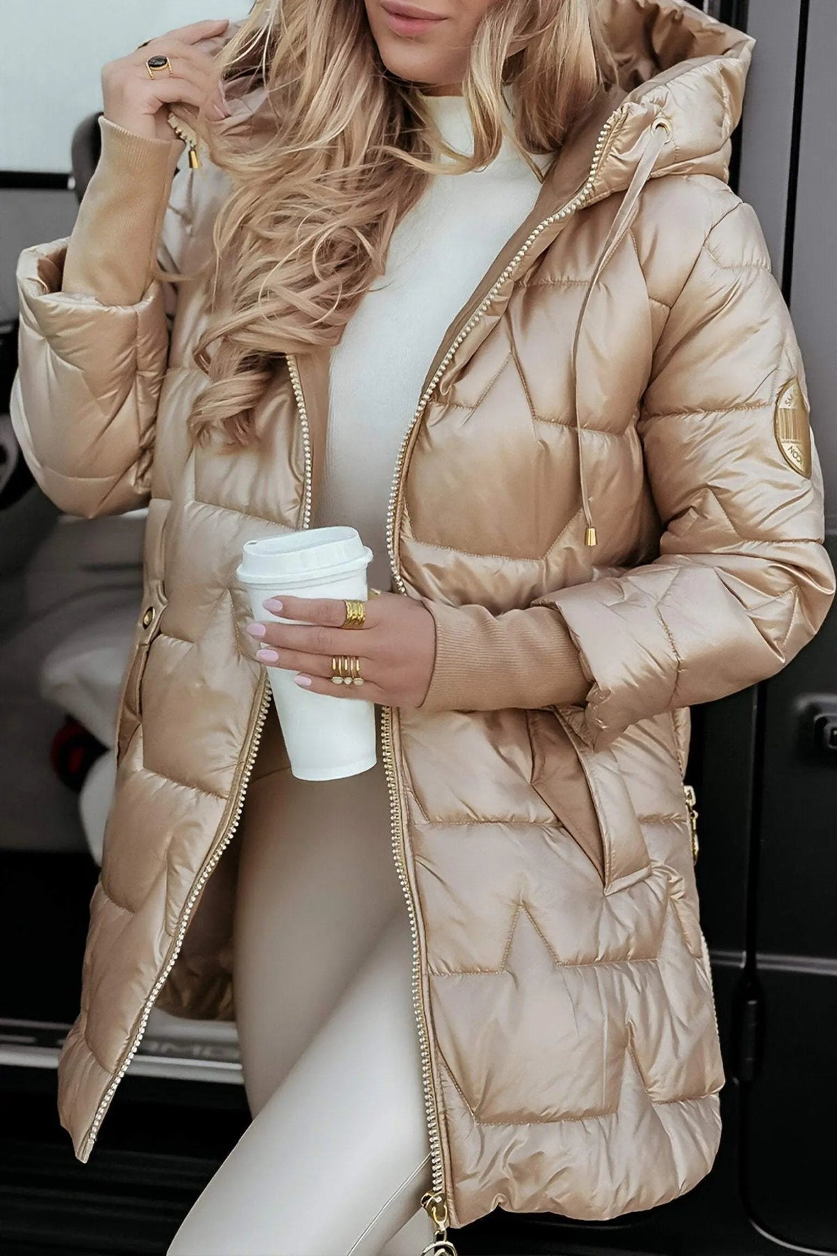 Light beige hooded puffer jacket with full zipper, drawstring hood, and gold trim