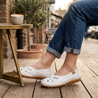 White leather slip-on loafers worn with cuffed blue jeans, perforated upper